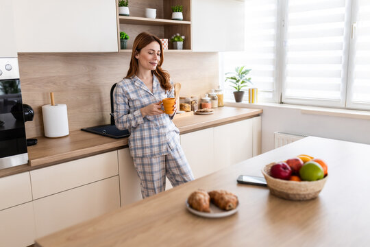 Woman enjoys coffee in modern kitchen at home