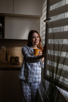 Woman gazes out window at dawn