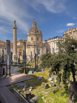Trajan's Column rises beside the Baroque dome of the Church of the Most Holy Name of Mary, overlooking the ancient ruins of Trajan's Forum in the heart of Rome, Italy.