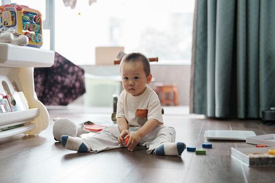 Little boy playing with colorful blocks on living room floor
