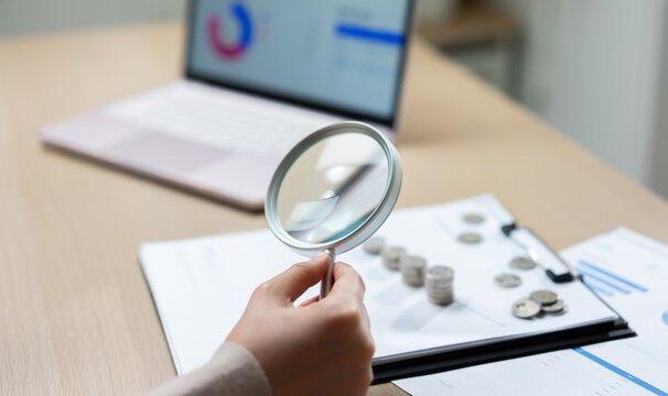 Financial audit and accounting analysis with magnifying glass examining coins and business reports, highlight budget review, expense verification, financial inspection, compliance, and corporate audit