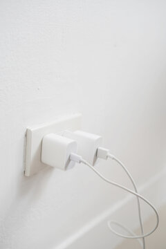 close up  plugging adapter charge the battery with outlet socket plug and hold mobile phone on wall ,electric safety concept