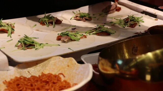 Pancake wrap with roasted duck and julienned cucumber street style assembled by gloved hands combining wrap, vegetable fillings and hand rolled