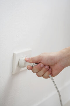 close up hand plugging adapter Electrical appliances with outlet socket plug ,electric safety concept