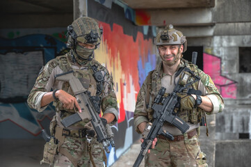 Fototapeta premium Male soldier in fully combat tactical military uniform and holding automatic war rifle, cautiously conducting a patrol and security sweep inside a ruined abandoned building