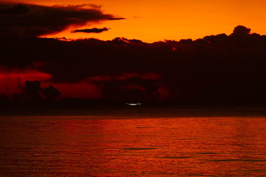 Dramatic orange and red sunset sky reflecting on calm sea water