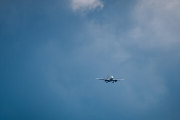Fototapeta premium Airplane flying through a clear blue sky with scattered clouds, showcasing the aircraft's wings and landing gear in a serene aerial environment
