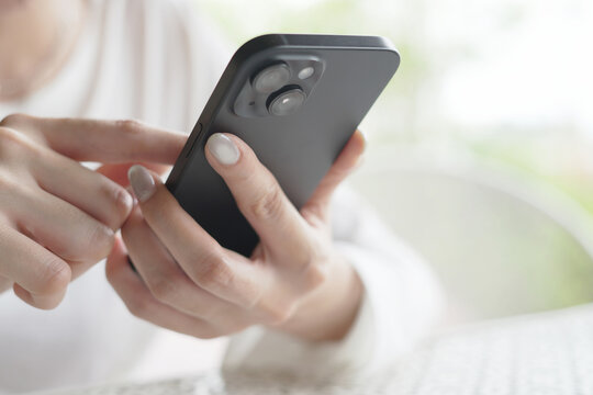 woman holds smart phone in her hands and scrolls through the news feed. Close up of hand uses mobile. point finger on screen, texting text message.