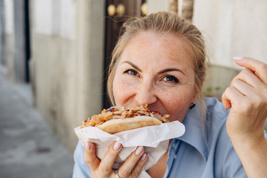 Woman Eating Grilled Chicken Shawarma Wrap With Yogurt Sauce Close up Street Food Bite , Sandwich Gyro or   Doner Kebab Outdoors