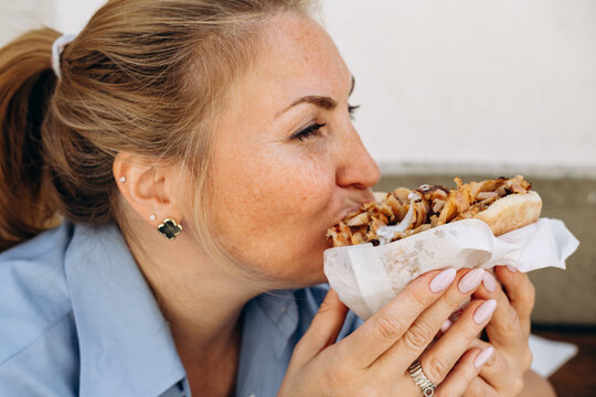 Woman Eating Grilled Chicken Shawarma Wrap With Yogurt Sauce Close up Street Food Bite , Sandwich Gyro or   Doner Kebab Outdoors