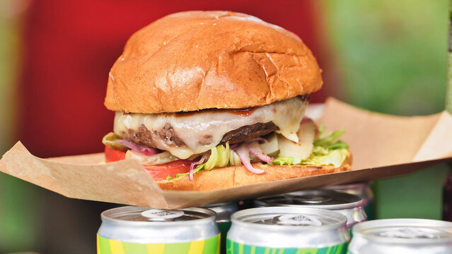 Juicy cheeseburger with melted cheese sitting on beverage cans