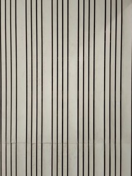 Texture of a minimalist light cream vertical wood panel wall with a clean and symmetrical repeating straight line pattern.