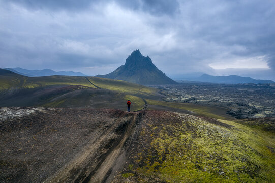 Lone hiker in red jacket facing Krakatindur, Iceland Highlands