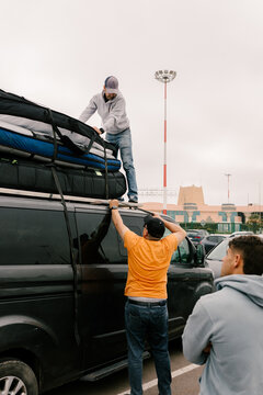 Friends secure surfboards on roof of a van to begin a trip in Morocco