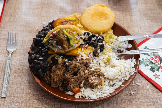 Venezuelan pabell&oacute;n with arepas, black beans, rice, and shredded beef