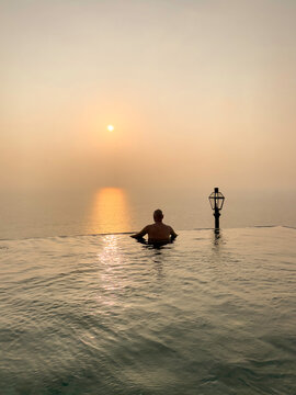 A man contemplate the sunset in an infinity pool overlooking the ocean