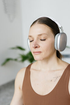 Cropped sportswoman with closed eyes listening something on headphones