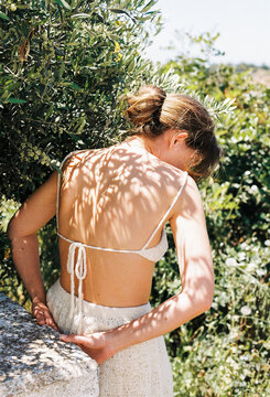 Woman in Summer Outfit Surrounded by Greenery in Bright Sunlight