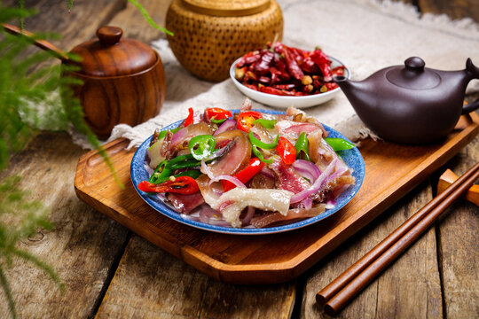 Spicy sliced pork with onions and chili peppers on a rustic table