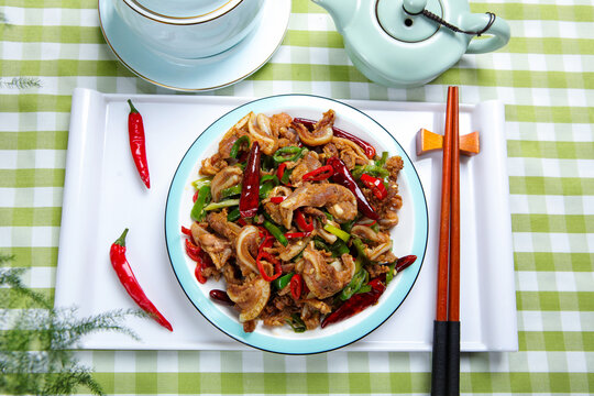 Spicy stir fried pork with chili peppers served with chopsticks and tea