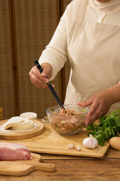 Preparing homemade pork dumpling filling with chopsticks in kitchen