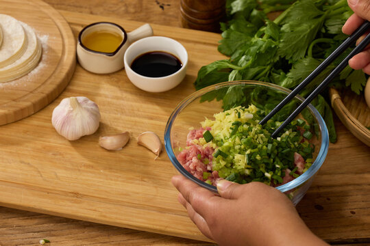 Preparing pork dumpling filling with scallions and ginger on wooden board