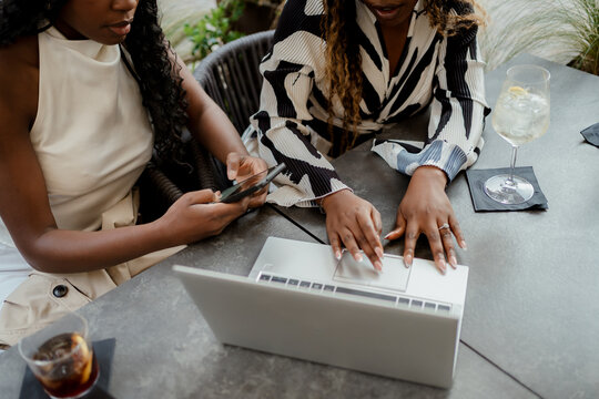 Anonymous women using technology in a bar outdoors in the city