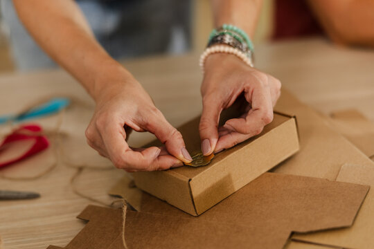 Female hands packaging a small box with string and label