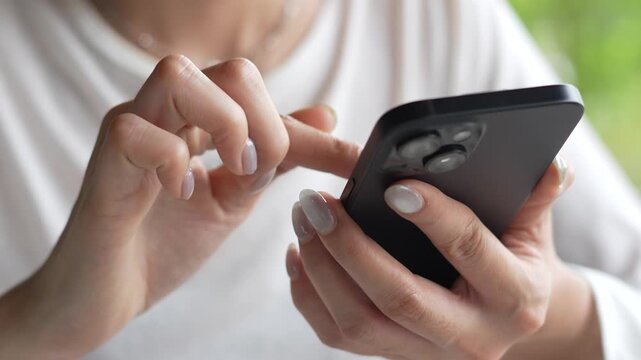 woman holds smart phone in her hands and scrolls through the news feed. Close up of hand uses mobile. point finger on screen, texting text message.