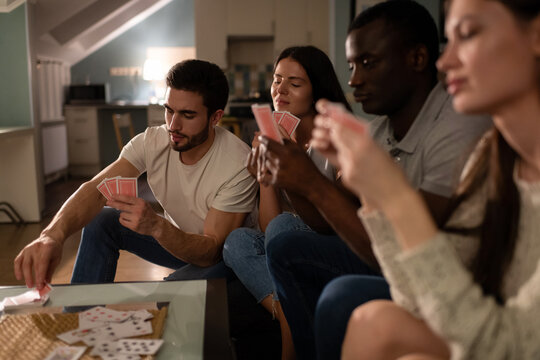 Bearded guy taking card from deck while playing game with friends 