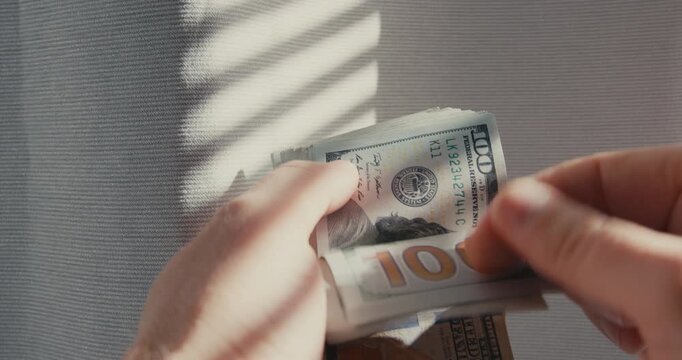 Male hands counting a stack of hundred dollar bills