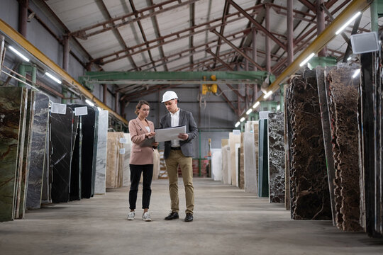 Male Manager showing draft to female client in warehouse
