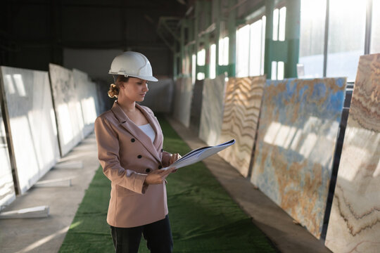 Concentrate female engineer reading blueprint in warehouse.