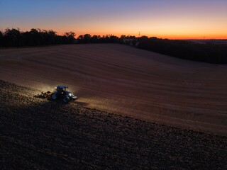 Travail de la terre en tracteur au coucher de soleil © Pierre
