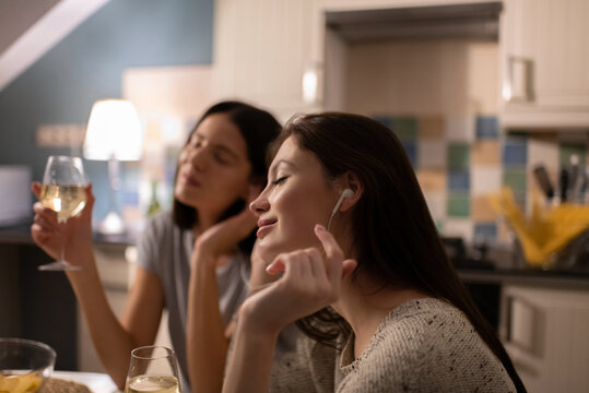Young female enjoying music near friend