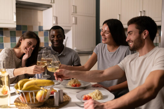 Multiracial friends clinking wineglasses during dinner