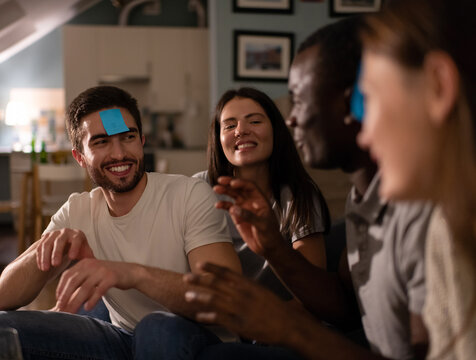 Cheerful guy playing guessing game with friends