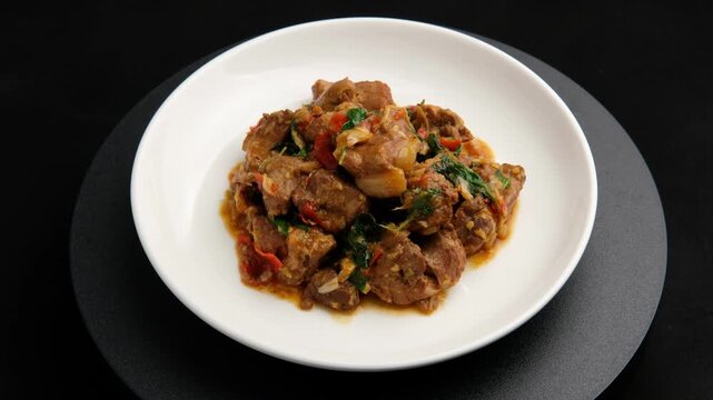Close up Stir fried Braised pork spare ribs with chilli and Thai holy basil in white plate.(pad kra pao moo tun)