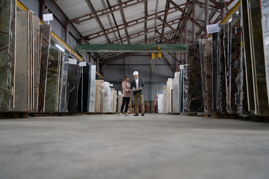 Male and Female Architects discussing blueprint in warehouse