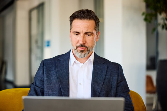 Businessman sits on the sofa, focused on his laptop