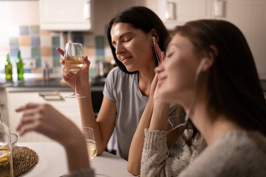 Young woman enjoying wine and music near friend