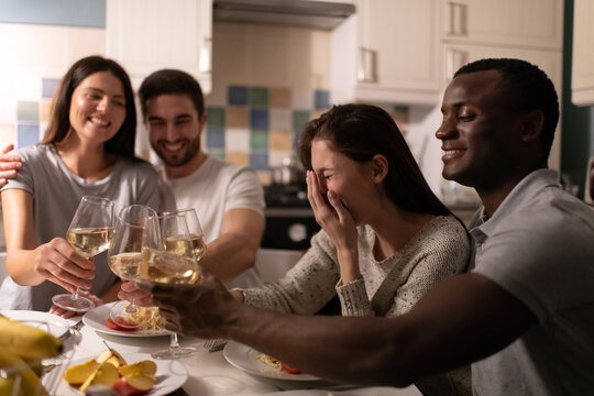 Young woman laughing while drinking wine with friends 