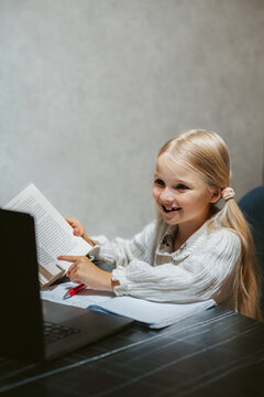 Child girl studying in online school platform using laptop homeschooling digital education class, smart kid reading book and learning course selfstudy at home modern technology connection
