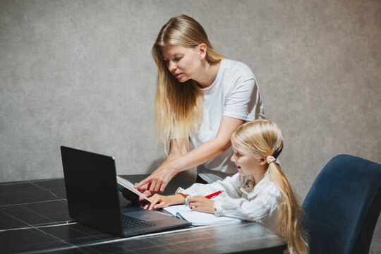 Mother helping her daughter study lesson in online school with laptop at home, child using homeschooling digital education family lifestyle learning technology and parent tutor support