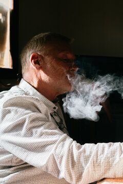 Man Exhaling Cigar Smoke