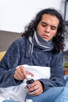 Young man measuring cough syrup feeling unwell