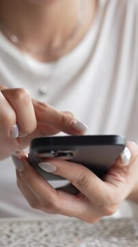 woman holds smart phone in her hands and scrolls through the news feed. Close up of hand uses mobile. point finger on screen, texting text message.