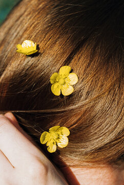 Three yellow buttercups nestled in flowing brown hair