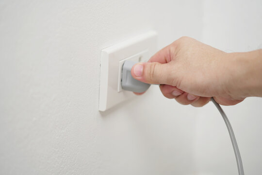 close up hand plugging adapter Electrical appliances with outlet socket plug ,electric safety concept