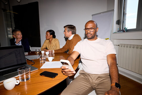 Man sits comfortably in a meeting room, uses his phone